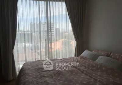 Cozy bedroom with large window offering city view and elegant curtains