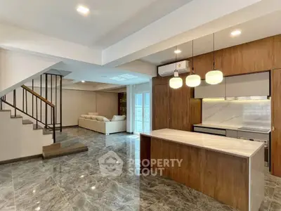 Modern open-plan living room with stylish kitchen and elegant staircase