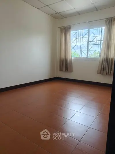 Spacious empty room with tiled floor and large window, perfect for customization.