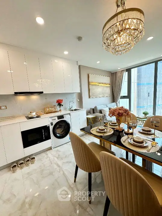 Luxurious open kitchen with dining area, modern appliances, and elegant chandelier.