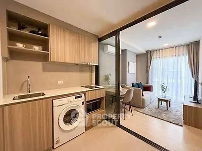 Modern open-layout kitchen with washing machine and cozy living room in stylish apartment.