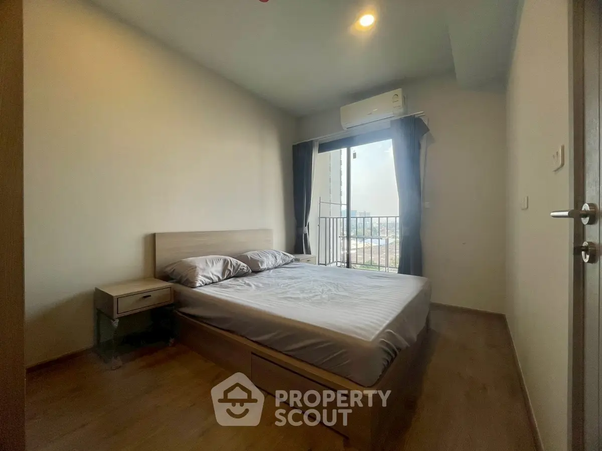 Cozy bedroom with modern furnishings and balcony view, perfect for urban living.