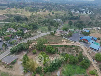 Aerial view of lush countryside with roads, houses, and greenery, ideal for real estate development.