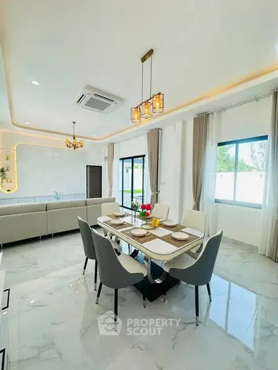 Elegant modern dining and living area with stylish lighting and marble flooring.