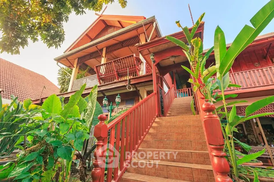 Charming tropical-style house with lush garden and inviting staircase entrance.