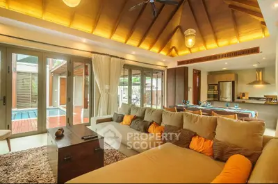 Luxurious open-plan living room with pool view, high ceilings, and modern kitchen.