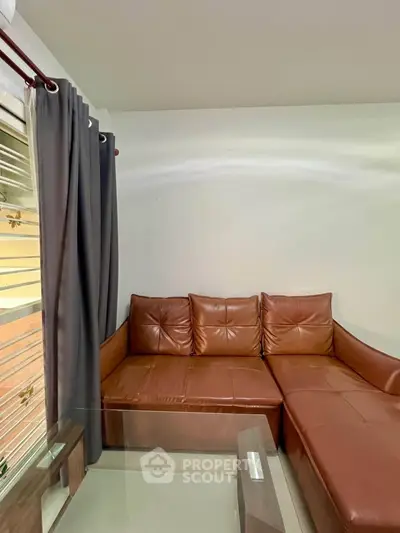 Modern living room with brown leather sectional sofa and glass coffee table.