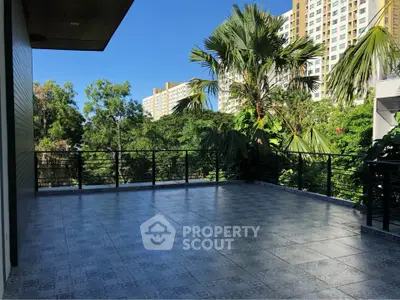 Spacious balcony with scenic view of lush greenery and modern high-rise buildings.
