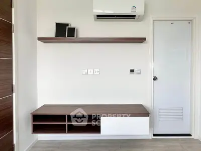 Modern minimalist interior with wall-mounted shelf and air conditioning unit.
