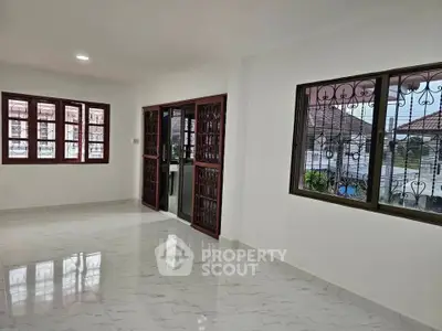 Spacious living room with large windows and tiled flooring in a modern home.