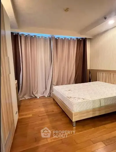 Spacious bedroom with wooden flooring and large window, perfect for natural light.