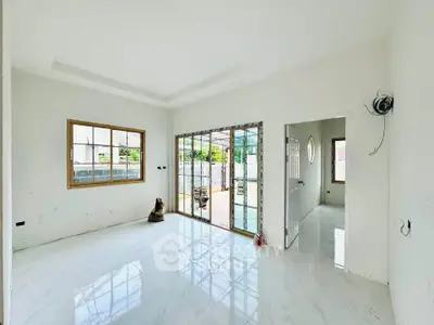 Bright and airy living room with large windows and sliding glass doors opening to a patio.
