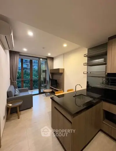 Modern open-layout living room with kitchen, featuring sleek design and balcony view.