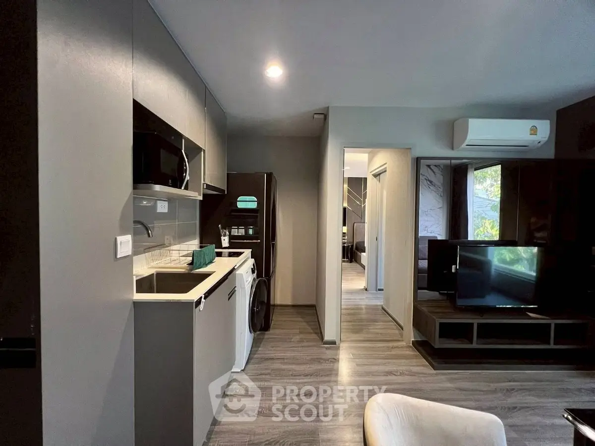 Modern apartment interior with sleek kitchen and cozy living area, featuring stylish appliances and contemporary design.
