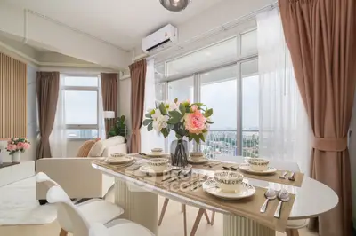 Elegant modern living room with dining area and panoramic city view, featuring stylish decor and natural light.