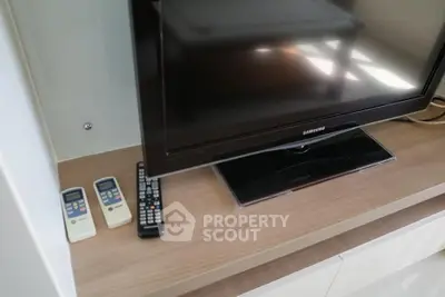 Modern living room with sleek TV setup and remote controls on wooden cabinet.