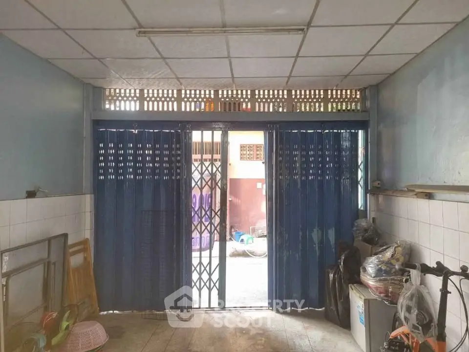 Spacious storage area with secure metal gate and tiled walls, ideal for versatile use.