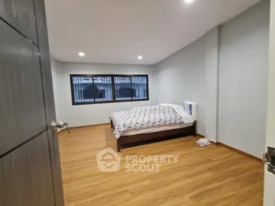 Spacious bedroom with wooden flooring and large window for natural light.