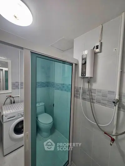 Compact bathroom with shower, washing machine, and modern water heater.