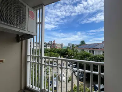 Charming balcony view overlooking lush greenery and cityscape under a bright blue sky.