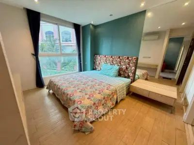 Spacious bedroom with large window and stylish decor in modern apartment.