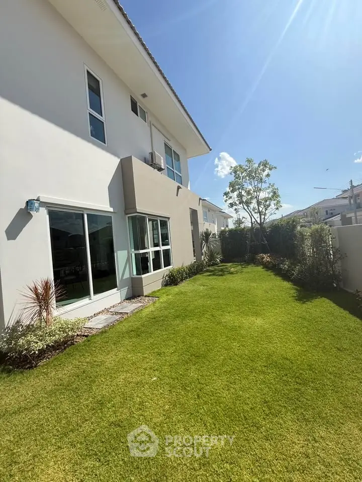 Stunning modern home exterior with lush green lawn and ample natural light.