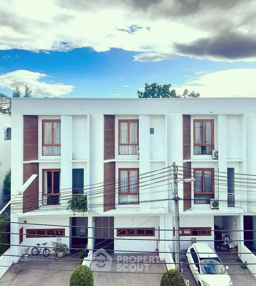 Modern townhouse exterior with clean lines and large windows under a vibrant sky.