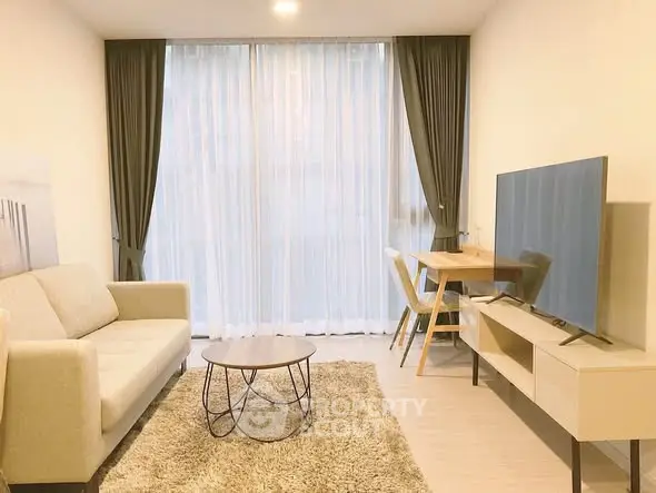 Modern living room with cozy sofa, stylish table, and large TV in a bright apartment.