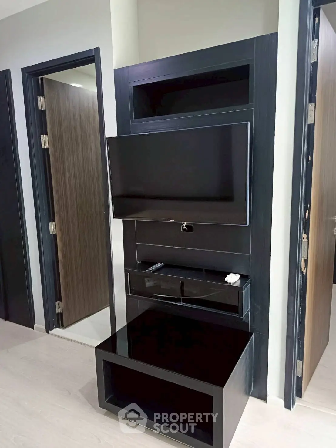 Modern living room with sleek TV unit and open doorways, showcasing contemporary interior design.