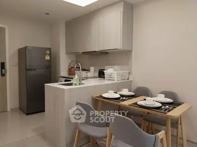 Modern kitchen with dining area featuring sleek cabinetry and stylish table setting.