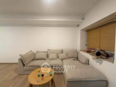 Cozy living room with beige sectional sofa and wooden table, perfect for relaxation.
