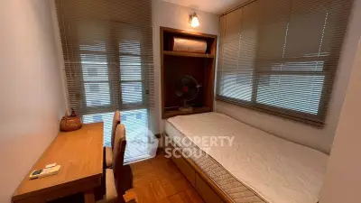 Cozy bedroom with wooden flooring, compact bed, and study desk, ideal for urban living.