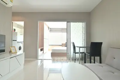 Modern living room with open layout, sleek furniture, and natural light leading to a cozy bedroom.