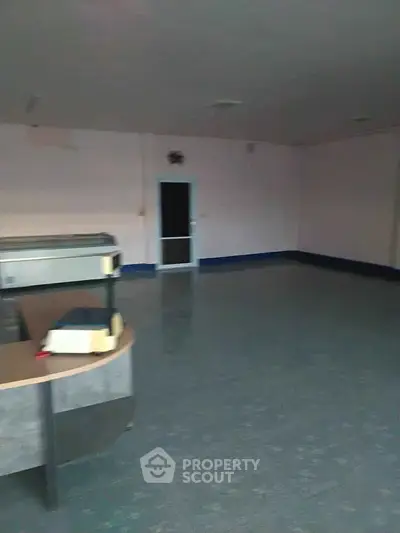 Spacious empty room with tiled flooring and a counter, ideal for commercial use.