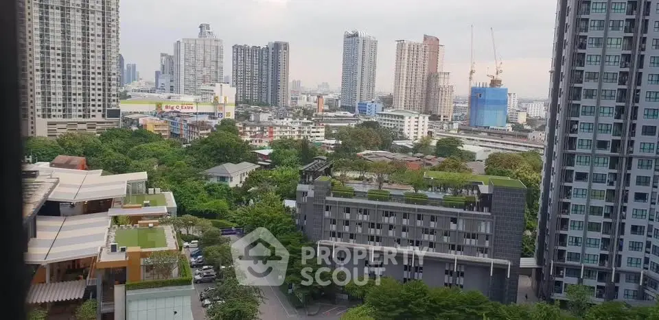 Stunning cityscape view from high-rise apartment showcasing urban skyline and lush greenery.
