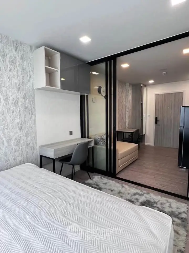Modern studio apartment with stylish decor and glass partition, featuring a cozy workspace and comfortable bed.