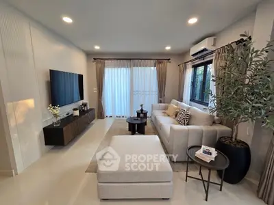Modern living room with stylish decor, large sofa, and natural light from floor-to-ceiling windows.