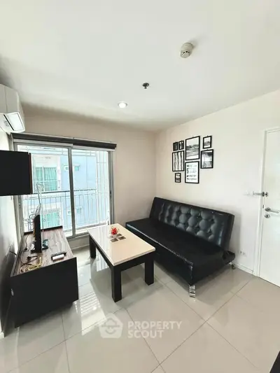 Modern living room with sleek black sofa, wall art, and large window offering natural light.