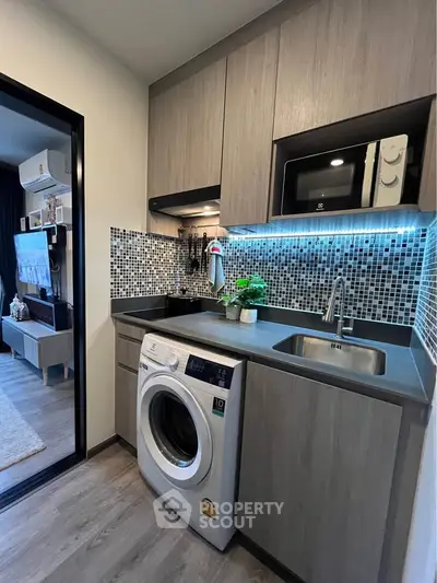Modern kitchen with washing machine and sleek cabinetry in stylish apartment