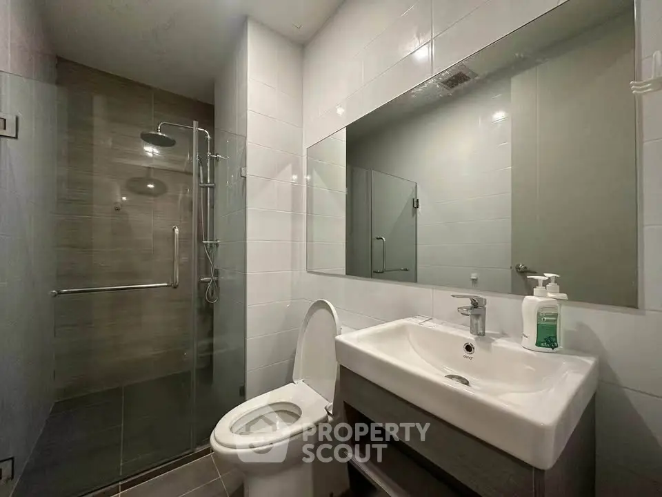 Modern bathroom with glass shower and sleek fixtures in contemporary apartment.