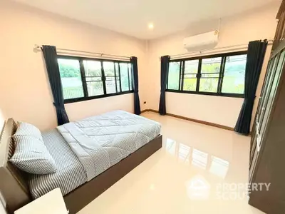 Spacious bedroom with large windows and modern furnishings in a serene setting.