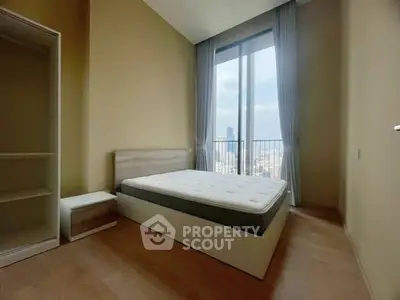 Spacious bedroom with city view and modern furnishings in high-rise apartment.
