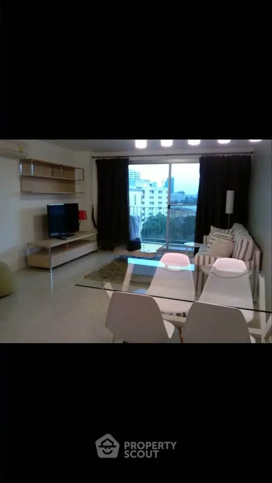Modern living room with glass dining table and city view balcony, perfect for urban living.