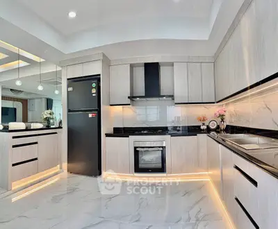 Modern kitchen with sleek cabinetry, black countertops, and built-in appliances in a spacious open layout.