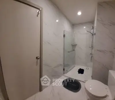 Modern bathroom with marble walls and glass shower enclosure