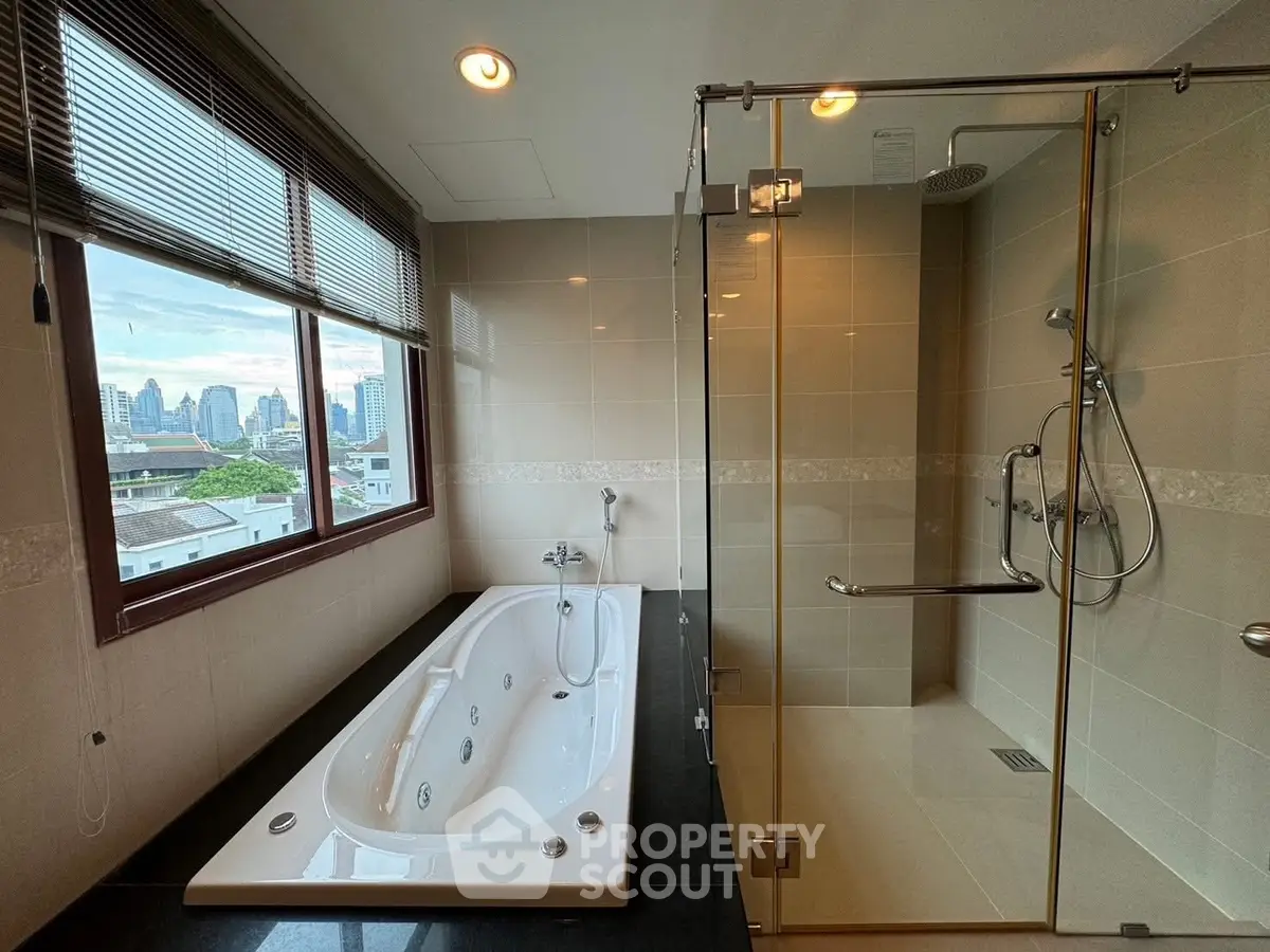 Luxurious bathroom with city view, featuring a spacious bathtub and modern shower enclosure.