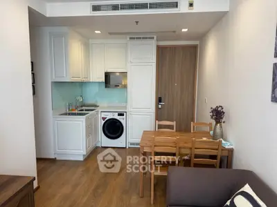 Charming compact kitchen with integrated appliances and cozy dining area in modern apartment.