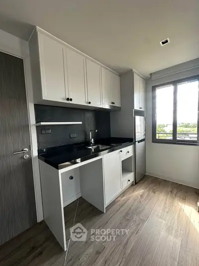 Modern kitchen with sleek cabinetry and large window offering natural light and scenic views.