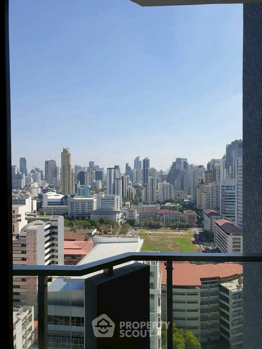 Stunning cityscape view from high-rise balcony with clear blue sky