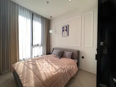 Modern bedroom with stylish decor and large window, featuring elegant curtains and cozy bedding.
